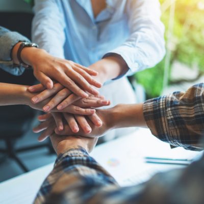 Closeup image of business team standing and joining their hands together in office